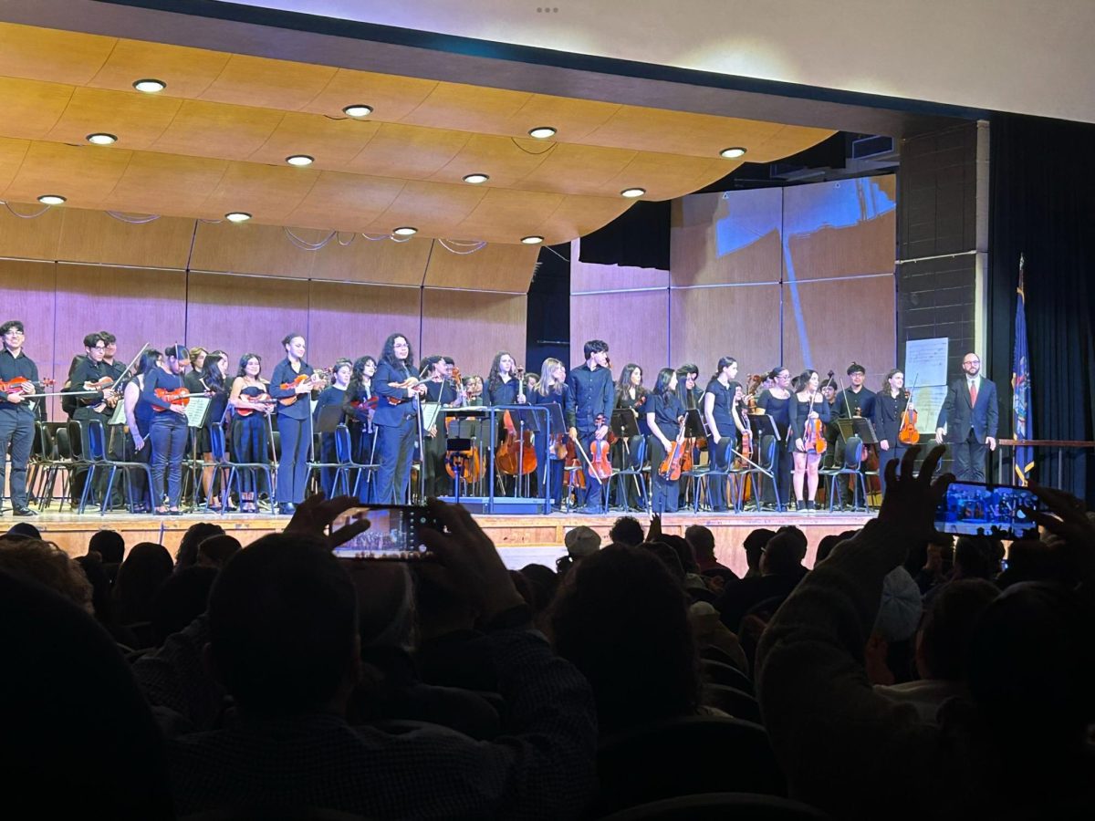 The symphony orchestra standing after their performance.