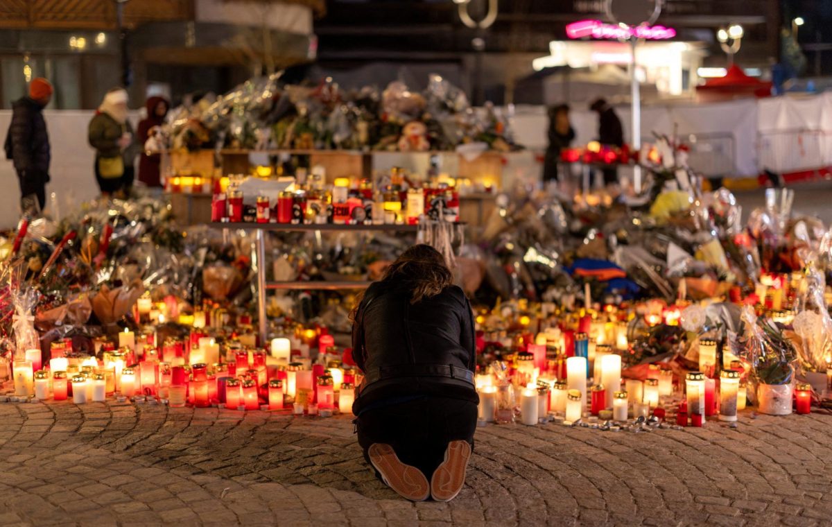 A woman lights a candle at a makeshift memorial outside the "Le Constellation" bar, after a deadly fire and explosion during a New Year's Eve party, in the upscale ski resort of Crans-Montana in southwestern Switzerland, January 5, 2026. REUTERS/Umit Bektas